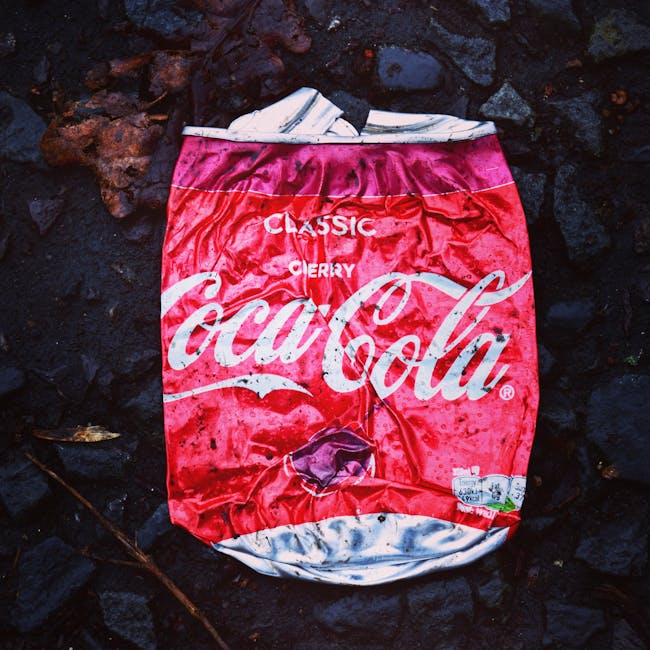 A black wheelie bin labeled 'St. John's' is positioned on the pavement at night, filled with various waste materials including cardboard boxes, plastic containers, and paper. The bin is situated on a 